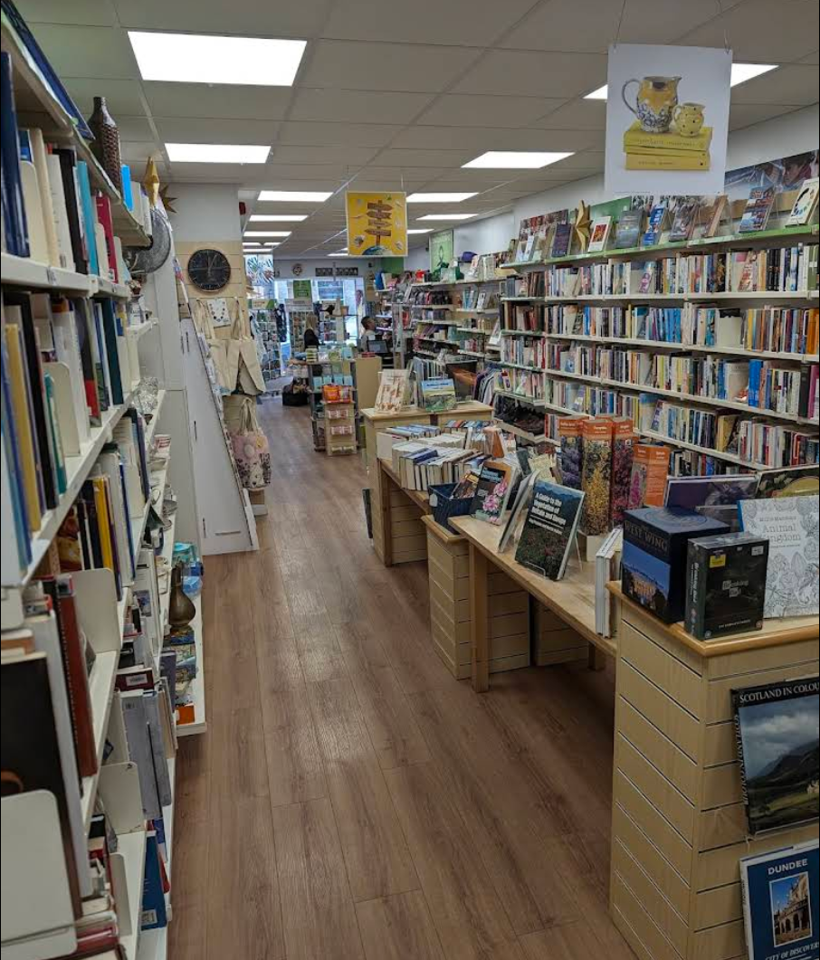 Interior of the Oxfam charity shop in St Andrews, Scotland, showing the shop floor with full, multi-level bookshelves on either side