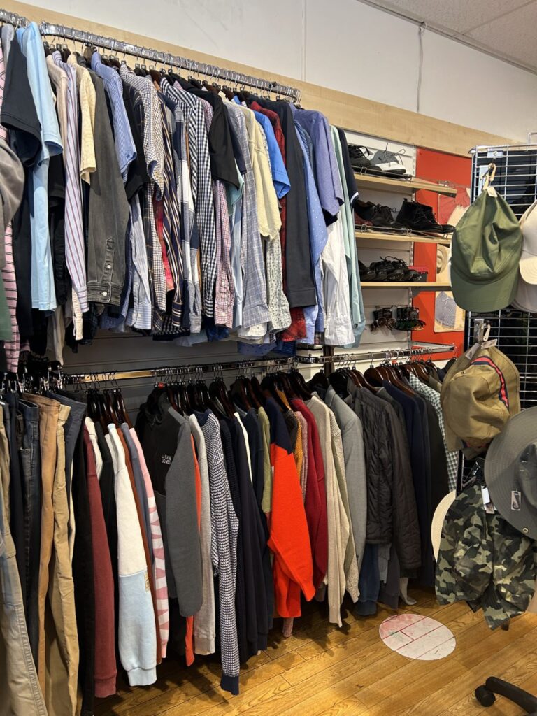Interior of the Barnardo's charity shop in St Andrews, Scotland, showing racks of second-hand mens clothing and shoes