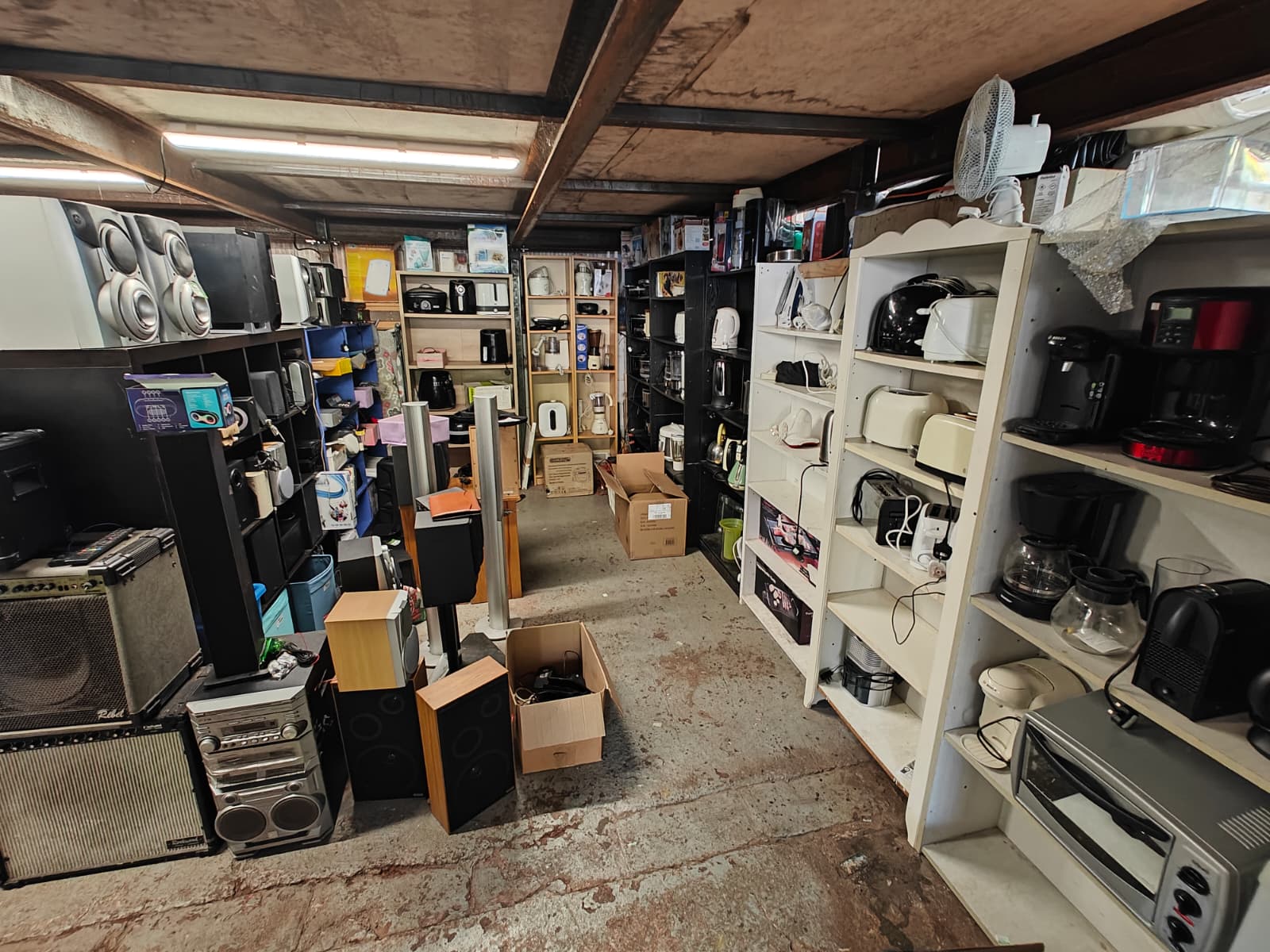 Second-hand electronics and home appliances displayed in a UK charity shop, including speakers, kettles, toasters, and coffee machines - promoting reuse and sustainable shopping.