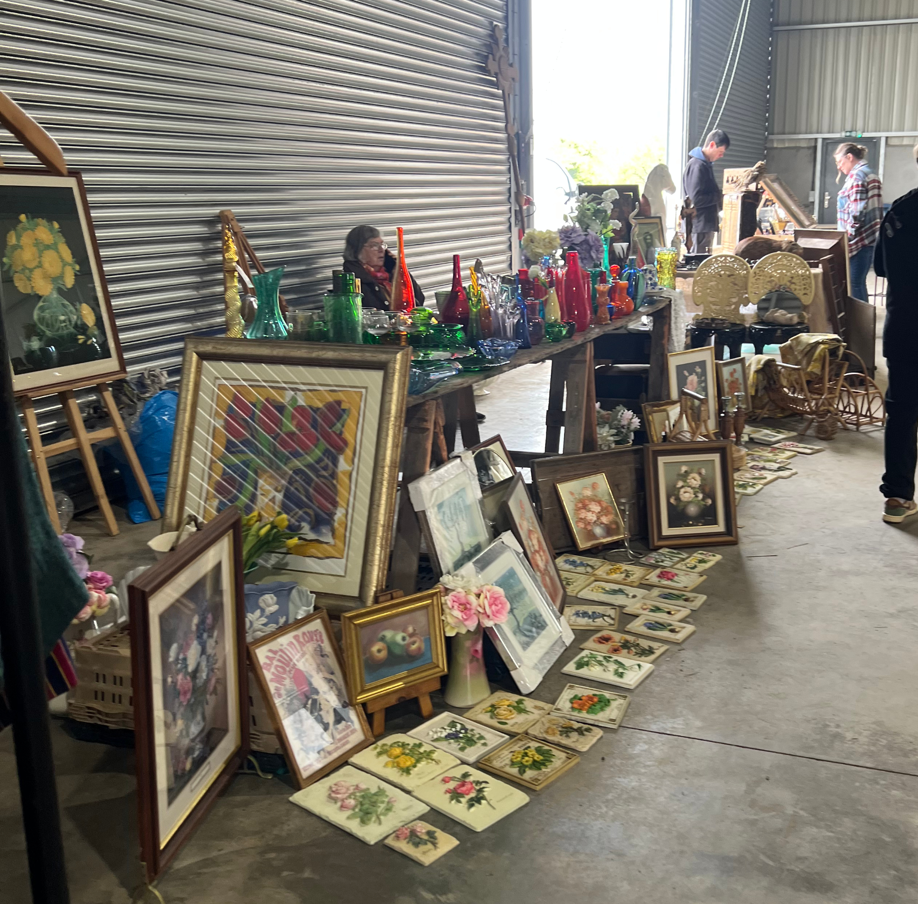 Indoor market stall selling pictures and colourful glassware
