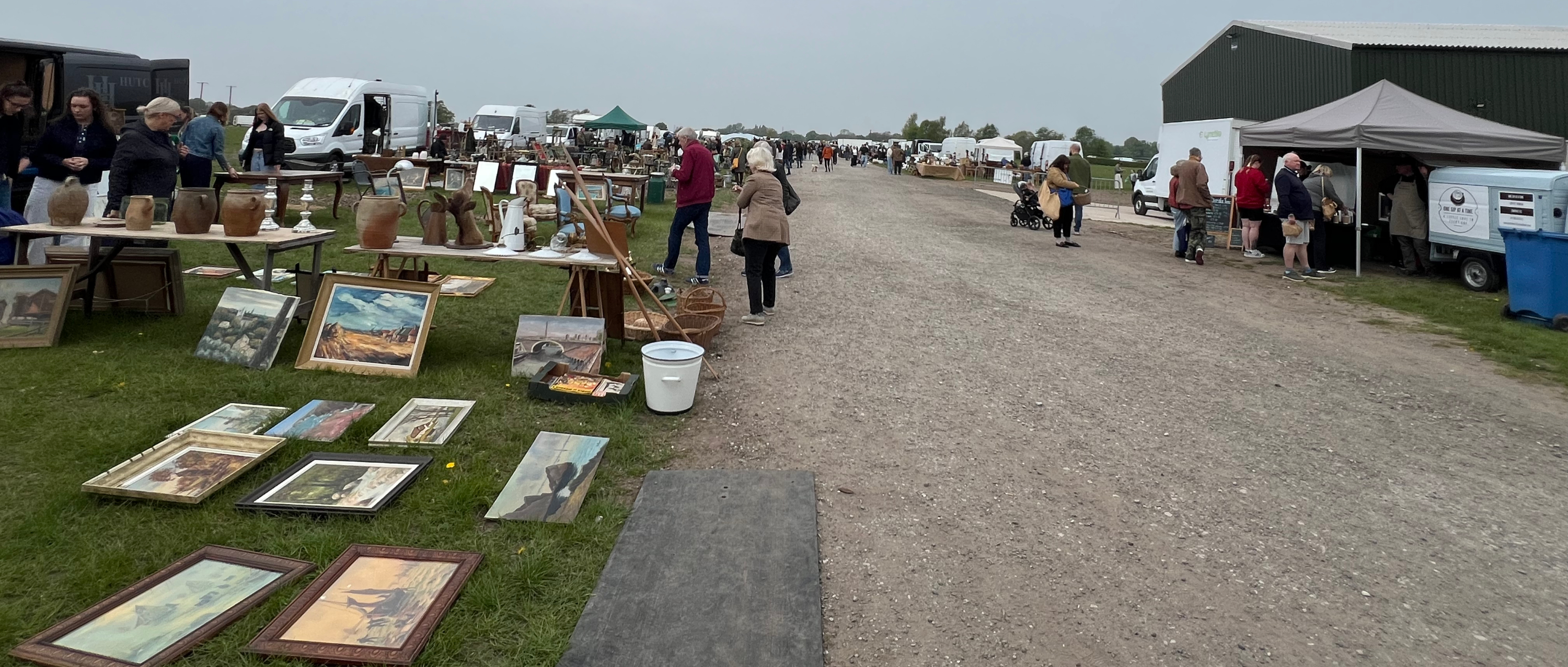 People shopping at antiques fair, looking at paintings and pots