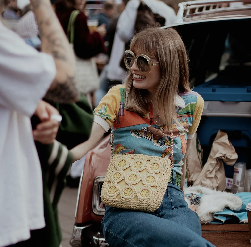 A stylish woman sitting at the back of a vintage car at a market in Leeds
