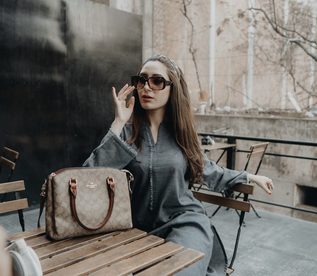 A woman sitting at a cafe in London with her second-hand luxury bag on the table