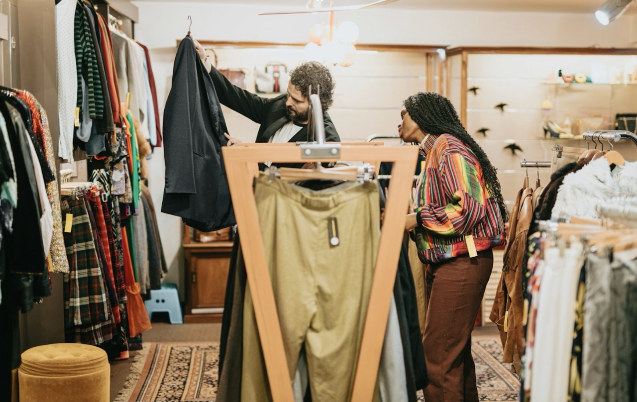 Two people looking through a clothes swap or charity shop rails for a bargain in London
