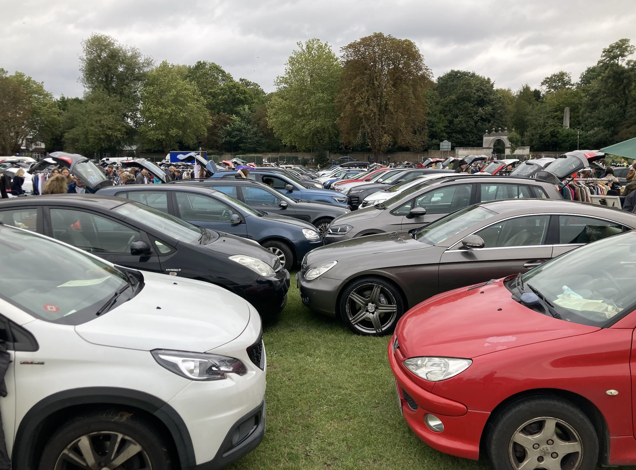 Large Chiswick Car Boot Sale with rows of parked cars on the school field and shoppers browsing second-hand stalls in West London.