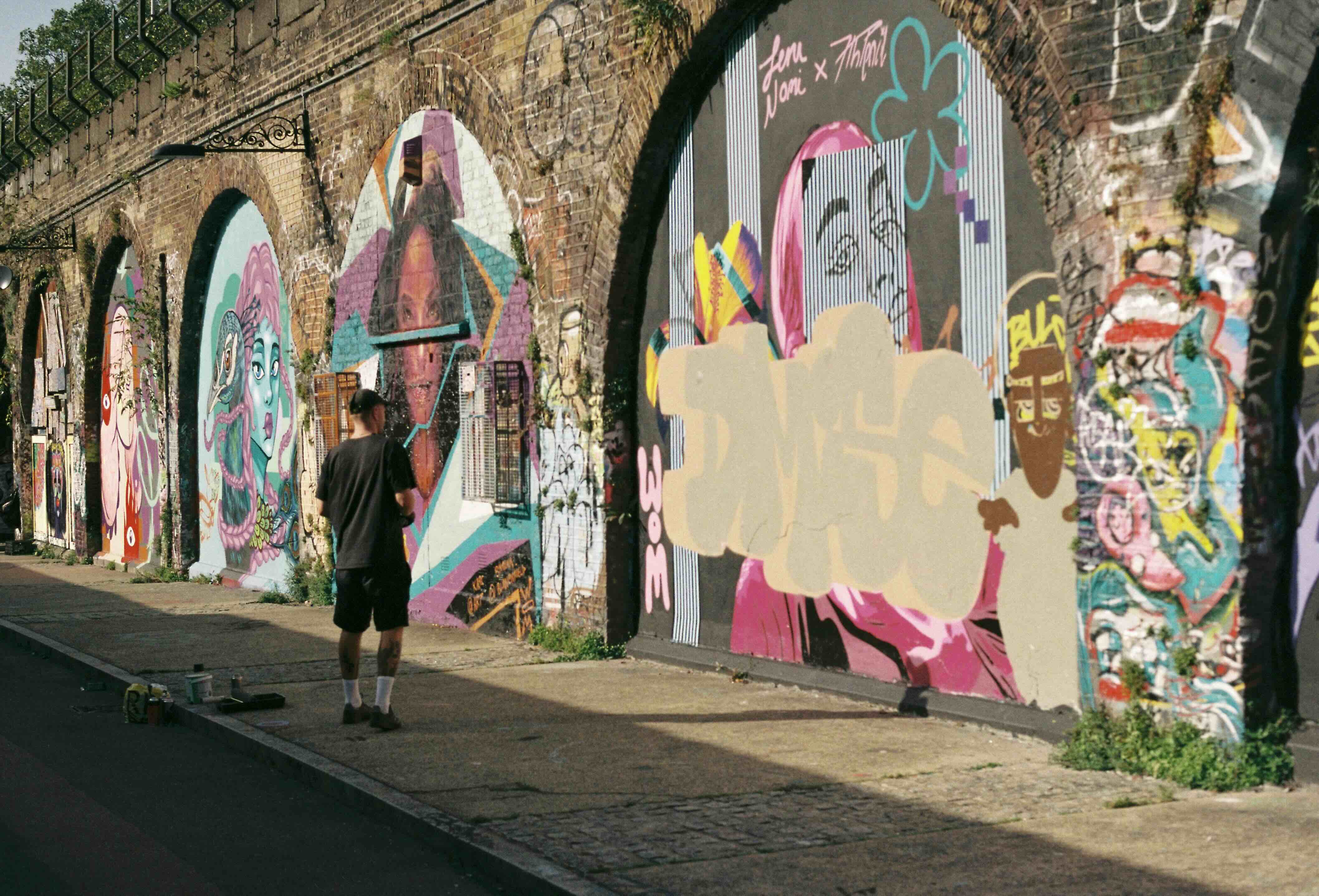 A man standing in front of beautiful graffitis in a back street of Peckham, London