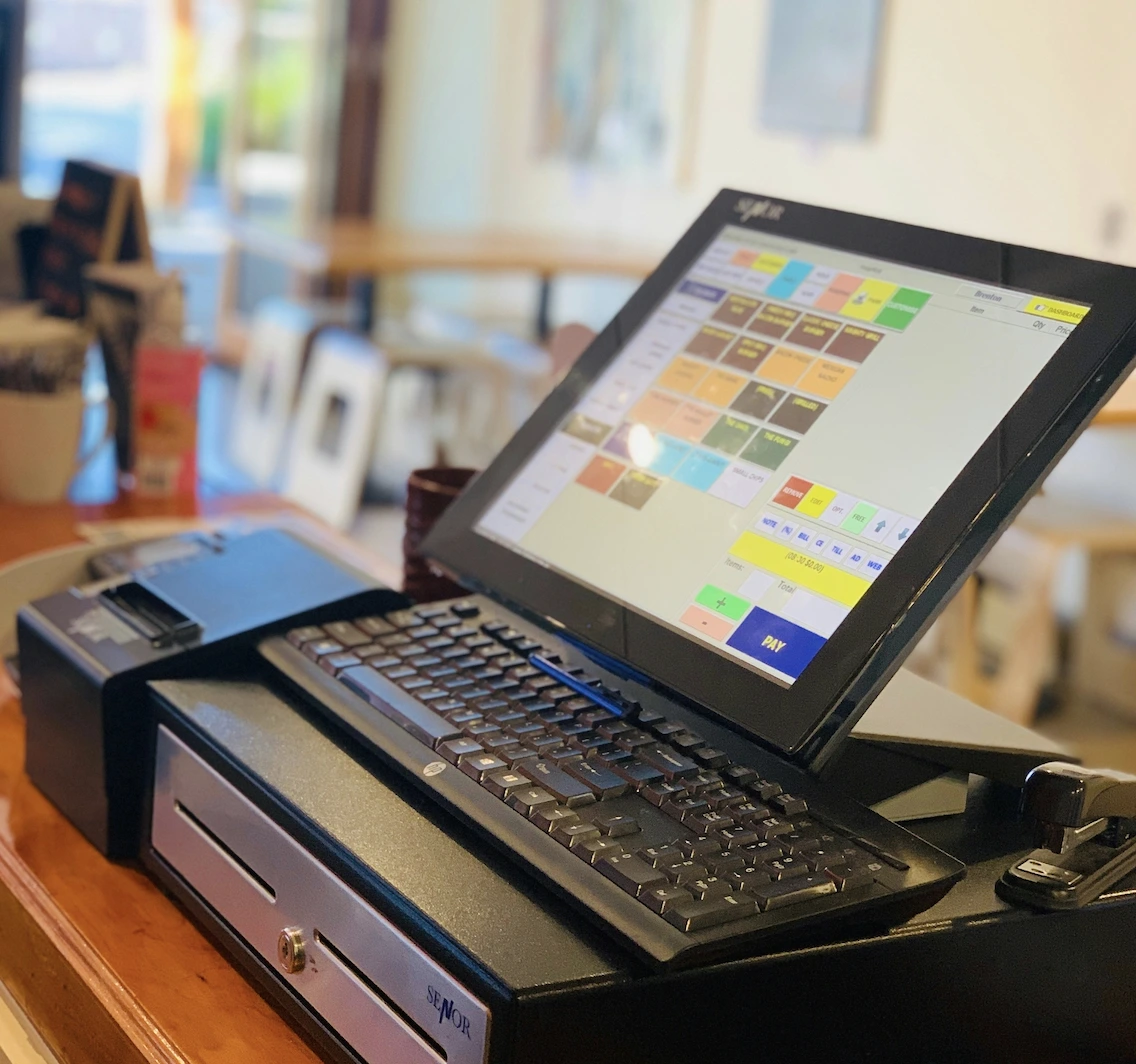 Touchscreen POS till system with cash drawer, barcode scanner and keyboard on a charity shop counter.