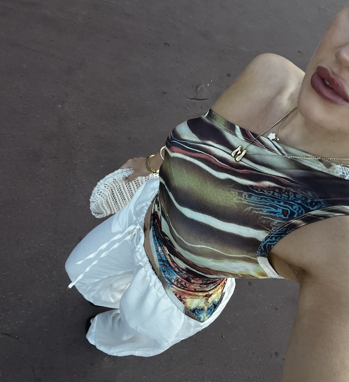 A stylish woman wearing a smart casual outfit taking a selfie in the street