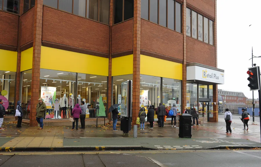 People queuing outside the Compton Care Retail Plus charity shop on a rainy day in Wolverhampton