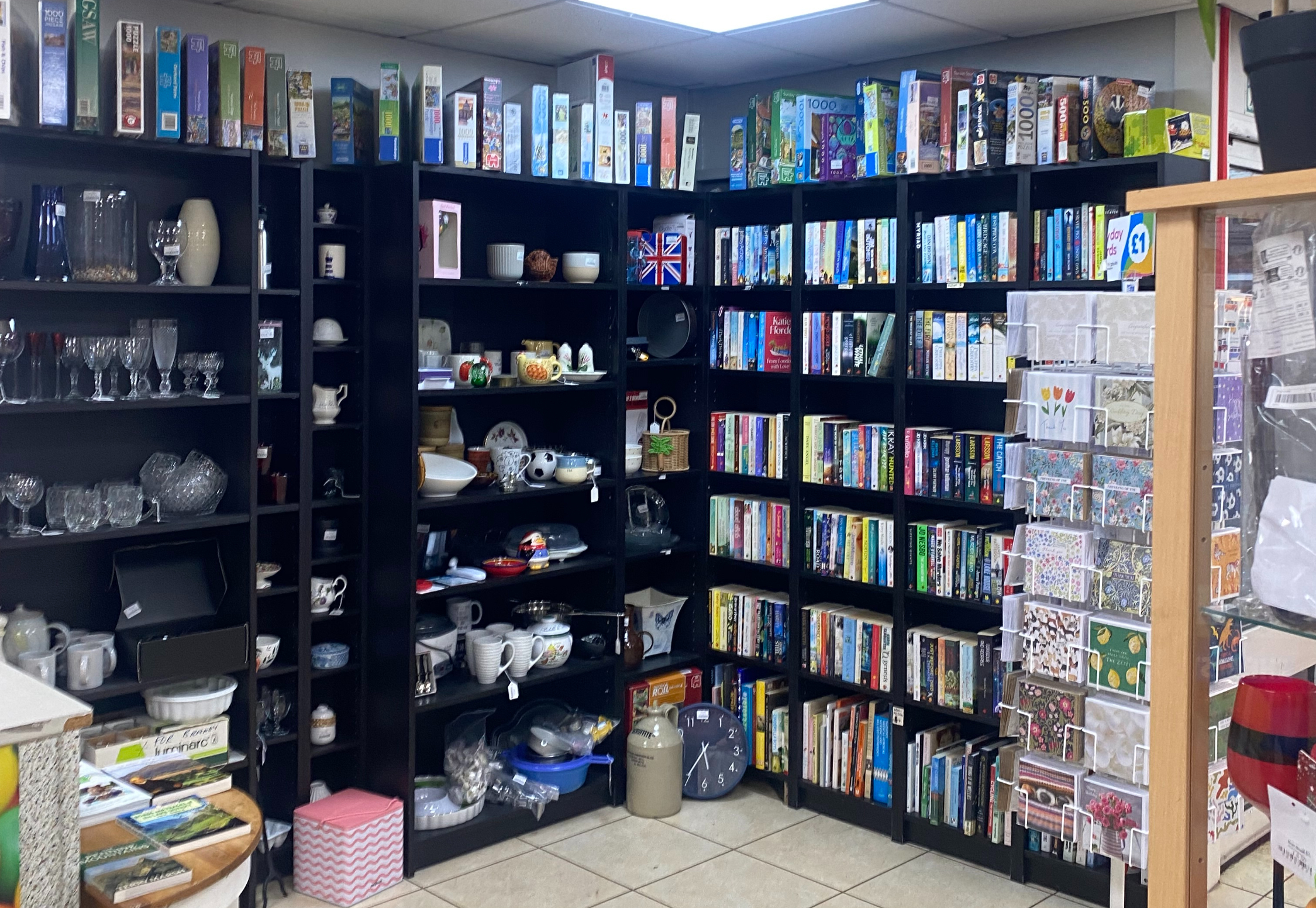 Shelves with homeware and second-hand books inside Hope House Charity Shop in Church Stretton, Shropshire