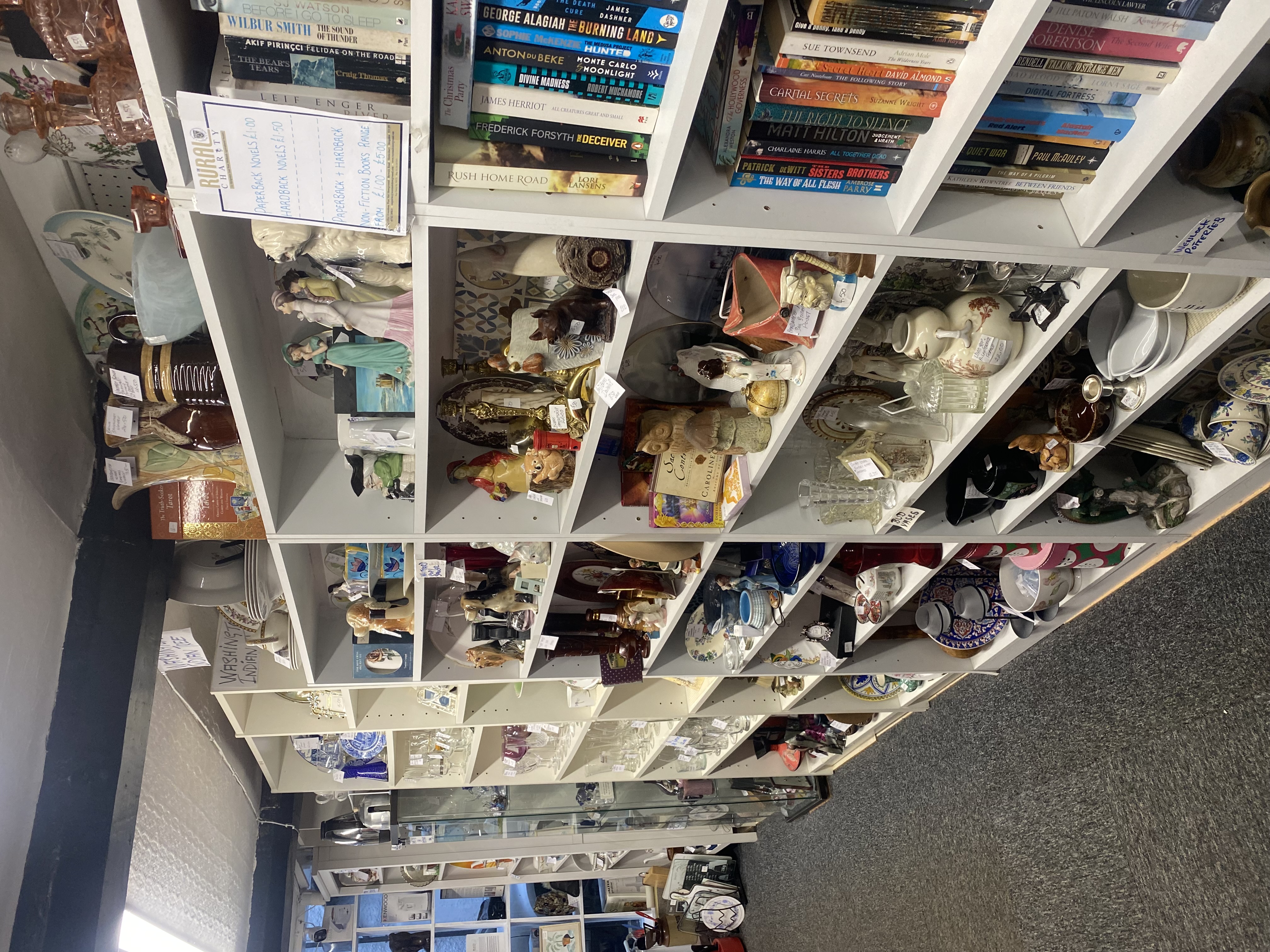 Inside The Rural Charity shop in Church Stretton, showing shelves of second-hand homeware, books and collectibles