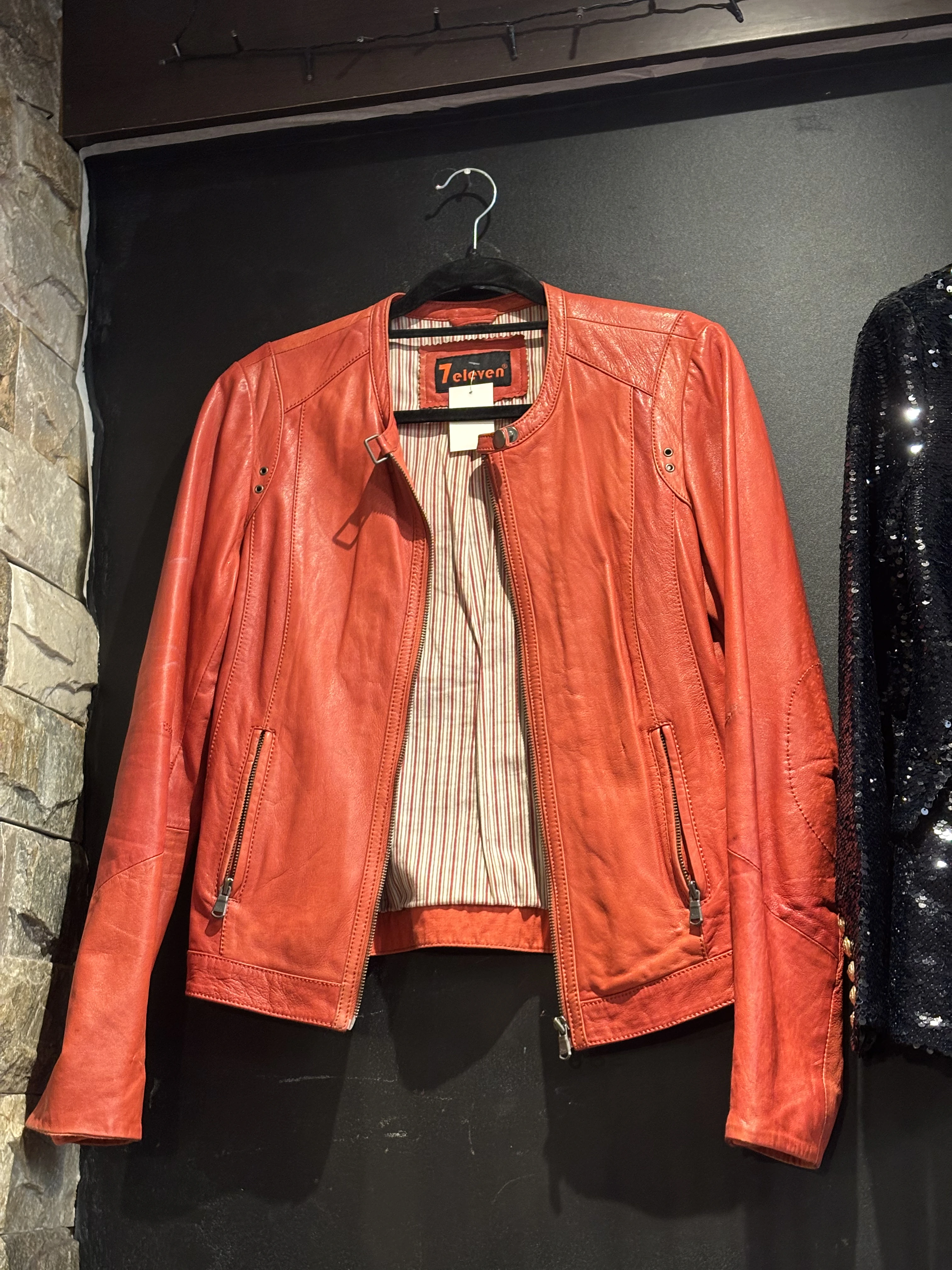 Orange vintage leather jacket on a hanger at a second-hand clothing pop-up