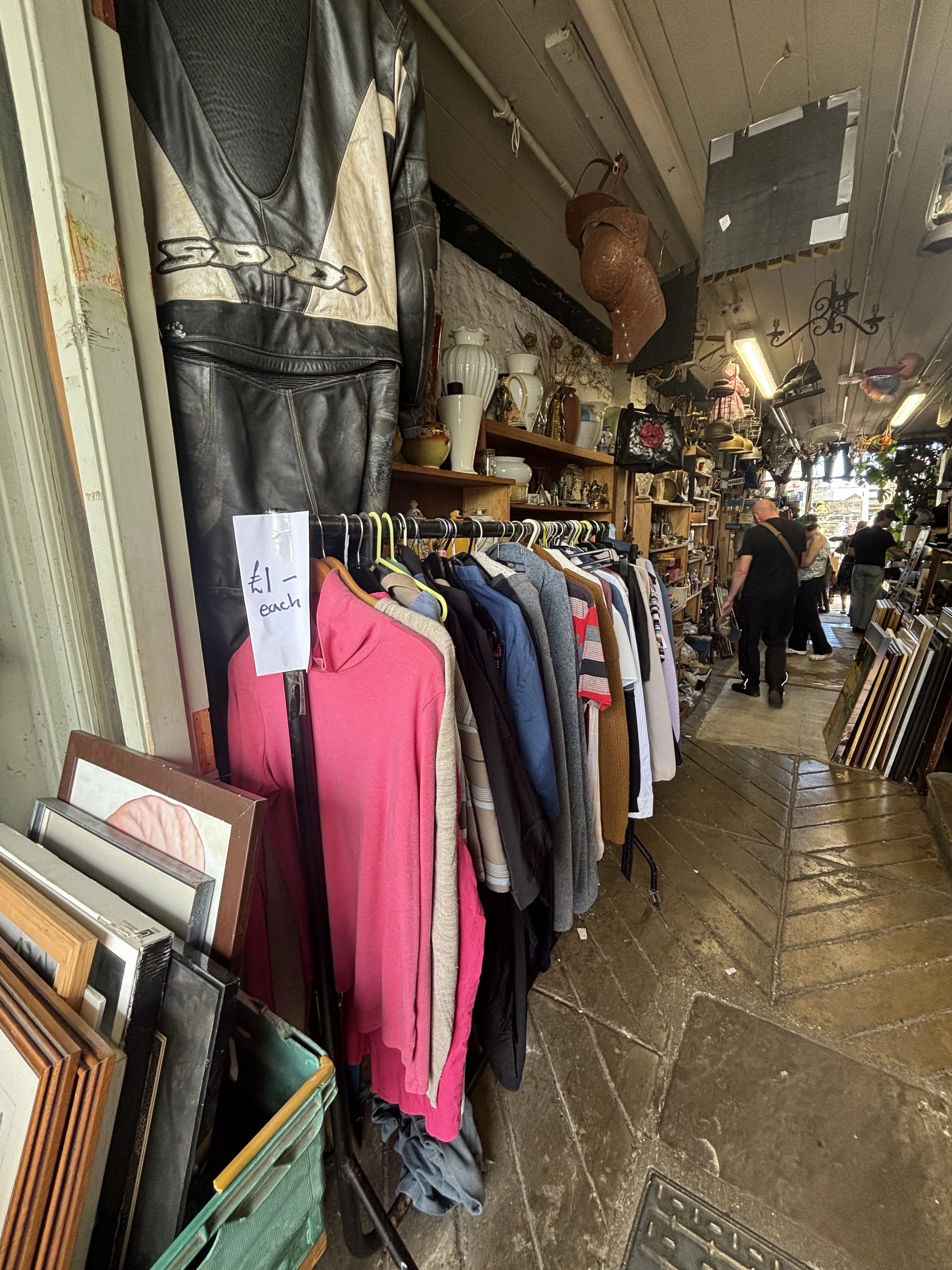 Vintage clothing rail with £1 items inside a busy indoor flea market in London.
